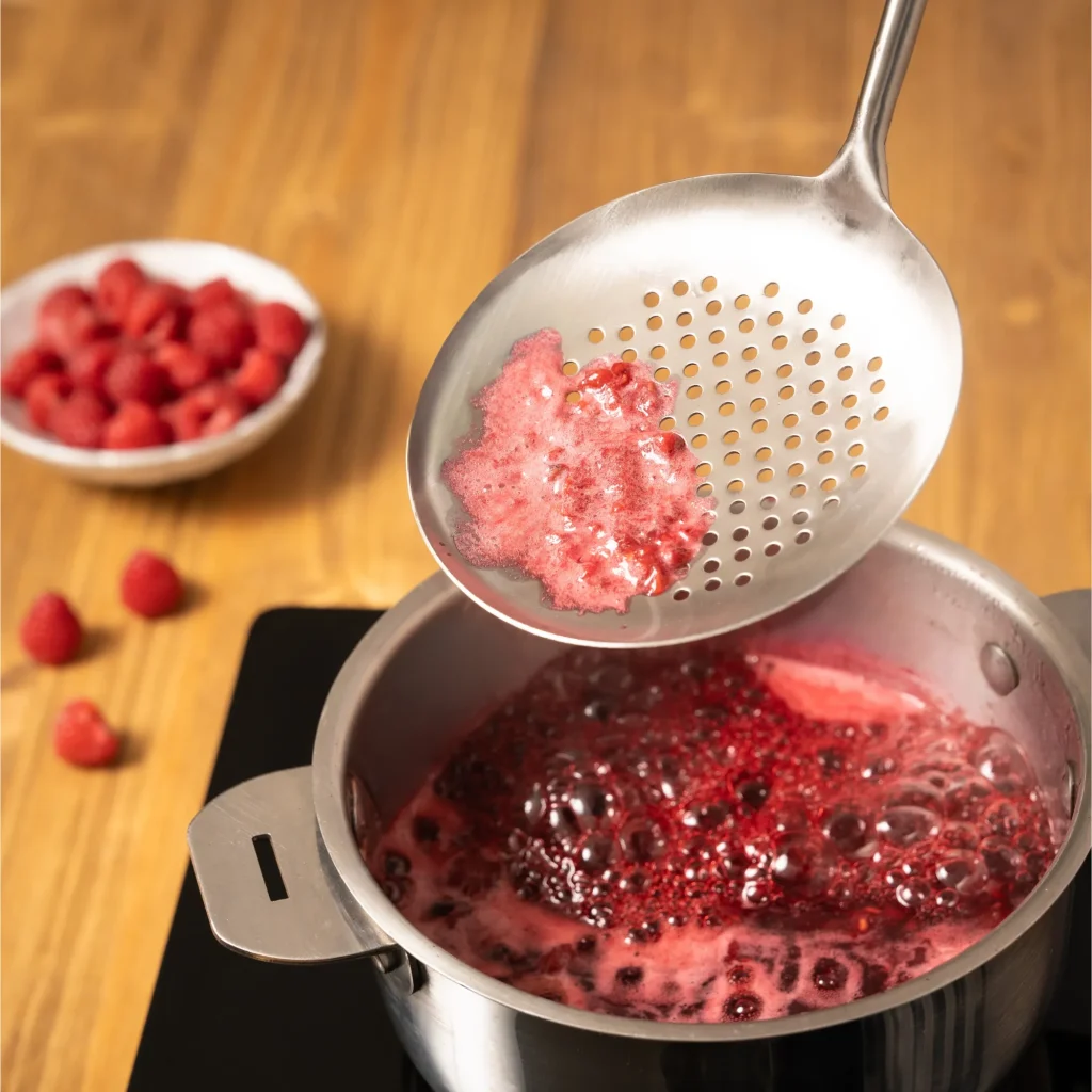 Écumoire retirant l’écume lors de la préparation d’une confiture maison